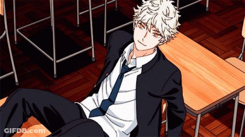 A Boy In A Suit And Tie Is Laying On A Desk GIF