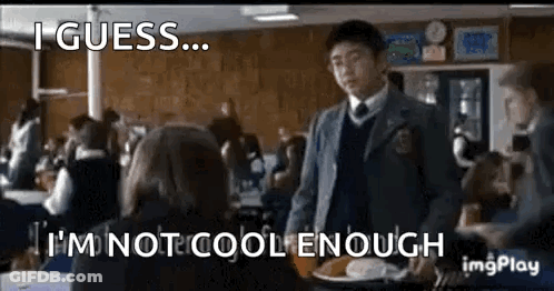 A Boy In A Suit And Tie Is Standing In Front Of A Girl In A Classroom . GIF