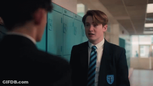 A Boy In A Suit And Tie Is Standing Next To A Boy In A Locker Room . GIF