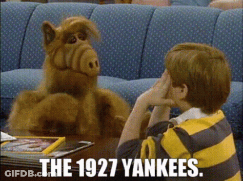 A Boy In A Yellow And Black Striped Shirt Is Sitting At A Table Talking To A Stuffed Animal . GIF