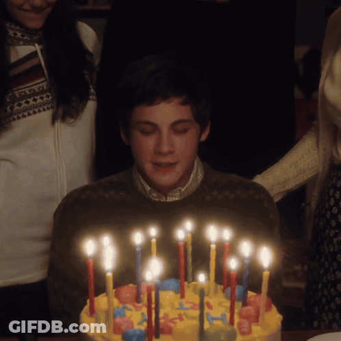 A Boy Is Blowing Out Candles On A Cake GIF
