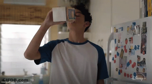 A Boy Is Drinking Milk From A Carton In Front Of A Disney + Fridge GIF