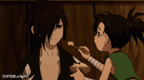 A Boy Is Feeding A Man A Bowl Of Food With Chopsticks GIF