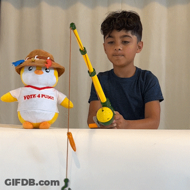 A Boy Is Holding A Fishing Rod Next To A Stuffed Penguin That Says Vote 4 Puget GIF