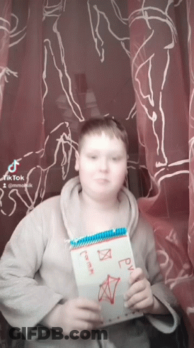 A Boy Is Holding A Notebook With A Drawing On It That Says ' Rv ' On It GIF