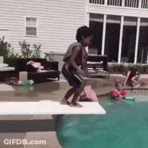 A Boy Is Jumping Into A Swimming Pool From A Diving Board . GIF