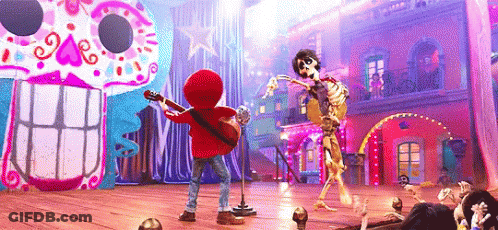 A Boy Is Playing A Guitar And Singing Into A Microphone While A Skeleton Is Dancing On A Stage . GIF