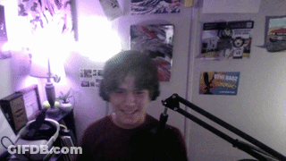 A Boy Is Smiling In Front Of A Microphone In A Room With Posters On The Wall Including One For Star Wars GIF
