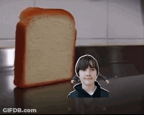 A Boy Is Standing Next To A Loaf Of Bread On A Counter GIF