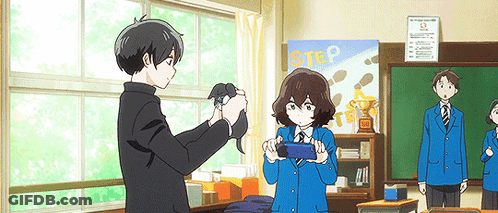 A Boy Is Taking A Picture Of A Girl In A Classroom With A Sign That Says Step In The Background . GIF