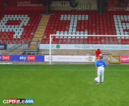 A Boy Kicking A Soccer Ball In Front Of A Sign That Says Johnston GIF
