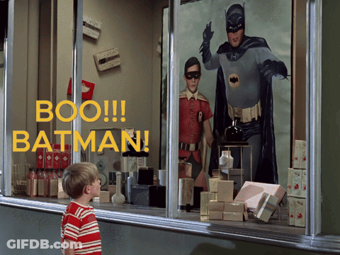A Boy Looks Out A Window At A Batman Display GIF