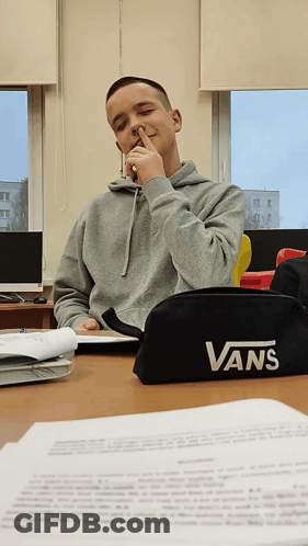 A Boy Sitting At A Desk With A Vans Pencil Case On It GIF