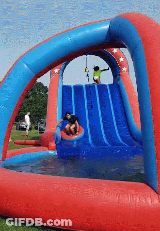 A Boy Slides Down A Red And Blue Water Slide GIF