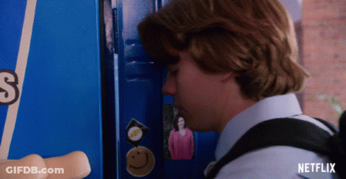 A Boy Standing In Front Of A Blue Locker With A Picture Of A Woman On It GIF