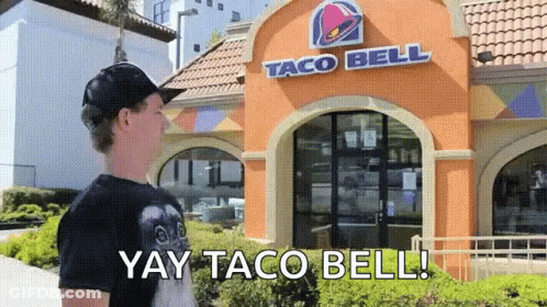 A Boy Standing In Front Of A Taco Bell Restaurant GIF