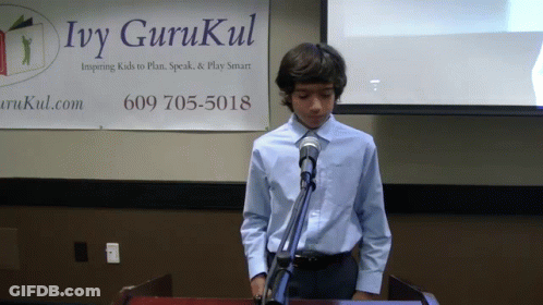 A Boy Stands At A Podium In Front Of An Ivy Gurukul Banner GIF