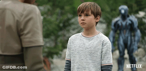 A Boy Stands In Front Of A Statue That Says Netflix On The Bottom GIF