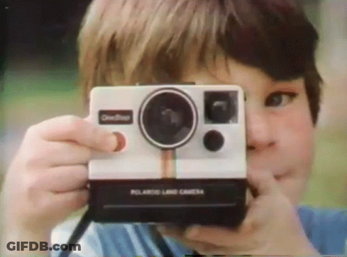 A Boy Taking A Picture With A Polaroid Land Camera GIF