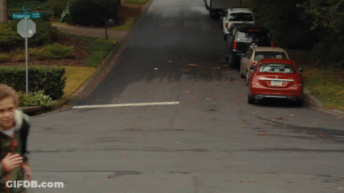 A Boy Walking Down A Street With A Sign That Says Federal St. GIF