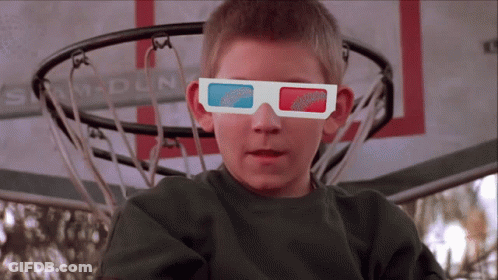 A Boy Wearing 3D Glasses Is Sitting In Front Of A Sam Dun Basketball Net GIF