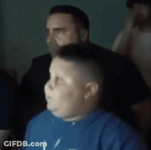 A Boy Wearing A Blue Shirt With The Letter V On It Looks At Something GIF