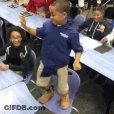 A Boy Wearing A Blue Shirt With The Word Tribe On It Stands In Front Of A Group Of Children GIF