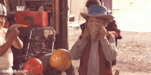 A Boy Wearing A Cowboy Hat Is Holding A Helmet In His Hand GIF