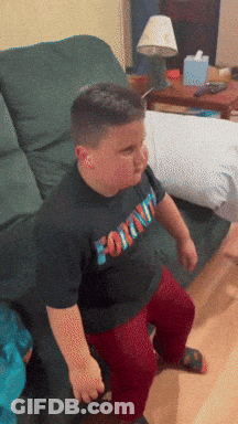 A Boy Wearing A Fortnite Shirt Sits On A Chair GIF