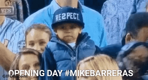 A Boy Wearing A Hat That Says Respect Is Sitting In A Crowd Of People . GIF
