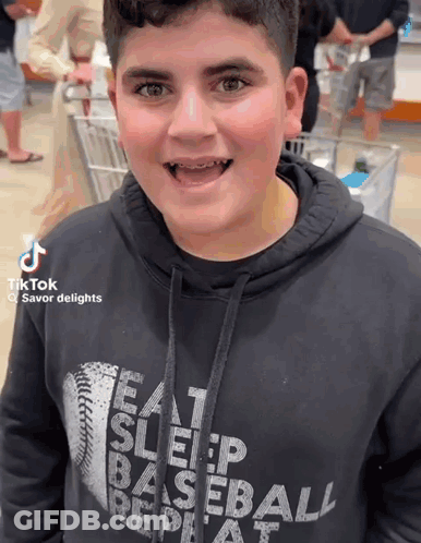 A Boy Wearing A Hoodie That Says Eat Sleep Baseball Repeat GIF
