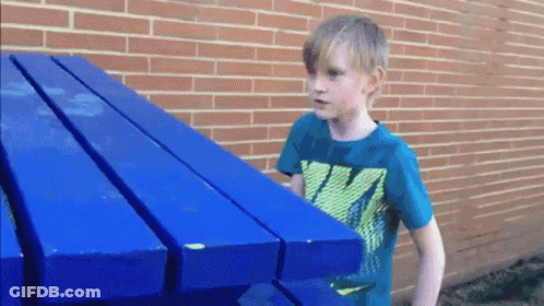 A Boy Wearing A Nike Shirt Holds A Blue Table GIF