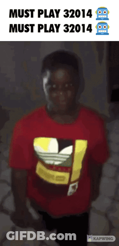 A Boy Wearing A Red Adidas Shirt Stands In Front Of A Sign That Says Must Play 32014 GIF