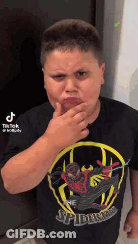 A Boy Wearing A Spiderman Shirt Is Making A Funny Face . GIF
