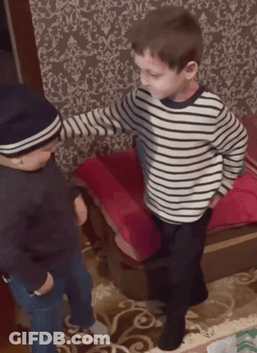 A Boy Wearing A Striped Shirt Is Standing Next To Another Boy Wearing A Hat GIF
