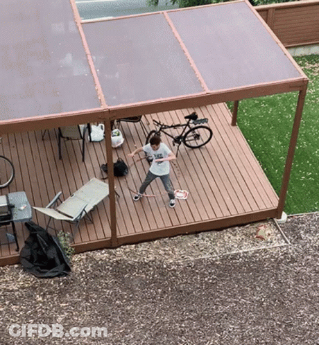 A Boy Wearing A T-Shirt That Says " I Love You " Is Playing Badminton On A Deck GIF