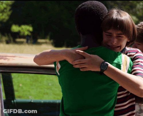 A Boy Wearing A Watch Is Hugging Another Boy In A Green Shirt GIF