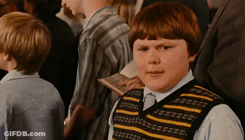 A Boy Wearing A Yellow And Black Striped Vest Looks At The Camera GIF