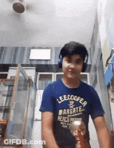 A Boy Wearing Headphones And A Lee Cooper Shirt Is Holding A Trophy GIF