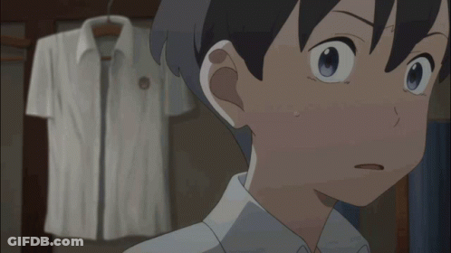 A Boy With A Surprised Look On His Face Stands In Front Of A White Shirt Hanging On A Rack GIF