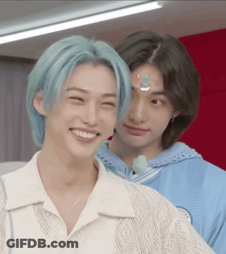 A Boy With Blue Hair Is Smiling Next To Another Boy With Black Hair . GIF