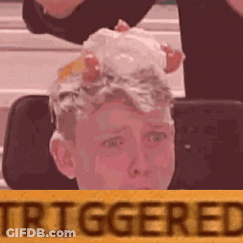 A Boy With Eggs On His Head Is Sitting In Front Of A Yellow Sign That Says Triggered . GIF