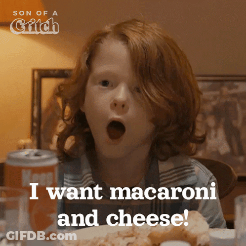 A Boy With Red Hair Is Sitting At A Table With His Mouth Open And Says " I Want Macaroni And Cheese " GIF