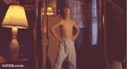 A Boy Without A Shirt Is Dancing In A Room With A Lamp GIF