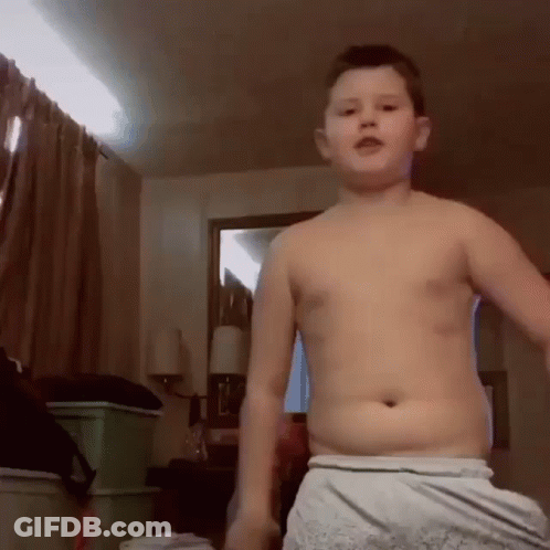 A Boy Without A Shirt Is Standing In A Room GIF
