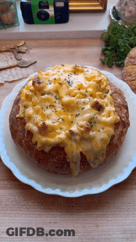 A Bread Bowl Filled With Macaroni And Cheese Is On A Plate GIF