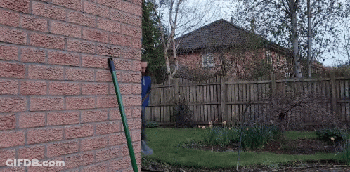 A Brick Wall With A Hose Attached To It In Front Of A House GIF