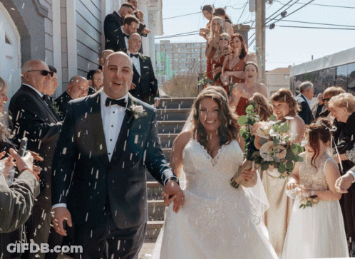A Bride And Groom Are Being Showered With Confetti By Their Wedding Guests GIF