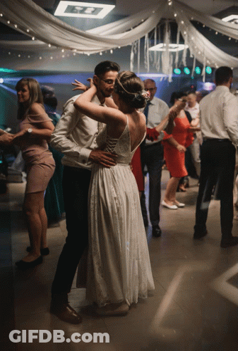 A Bride And Groom Are Dancing On A Dance Floor At A Wedding Reception GIF