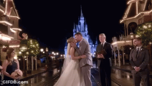 A Bride And Groom Are Kissing In Front Of A Castle GIF